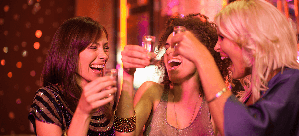 Women laughing and toasting with drinks.